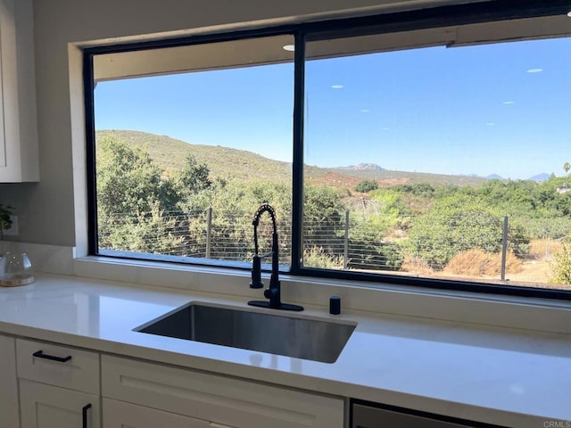 kitchen featuring white cabinetry, a mountain view, and sink