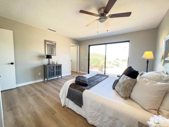 bedroom featuring hardwood / wood-style flooring, ceiling fan, a textured ceiling, and access to outside