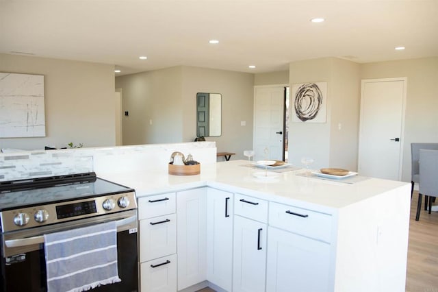 kitchen featuring stainless steel range with electric cooktop, white cabinets, and light wood-type flooring