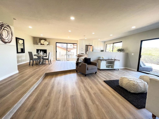 living room with a fireplace, light hardwood / wood-style floors, and a textured ceiling