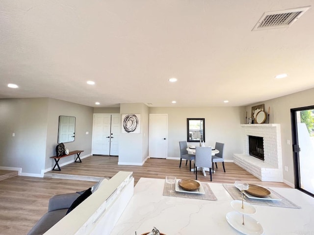 living room featuring a brick fireplace and light hardwood / wood-style flooring