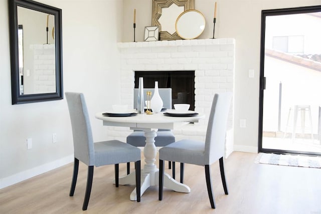 dining space featuring a fireplace and light hardwood / wood-style flooring