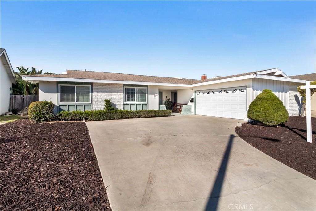 ranch-style house featuring driveway, brick siding, an attached garage, and fence