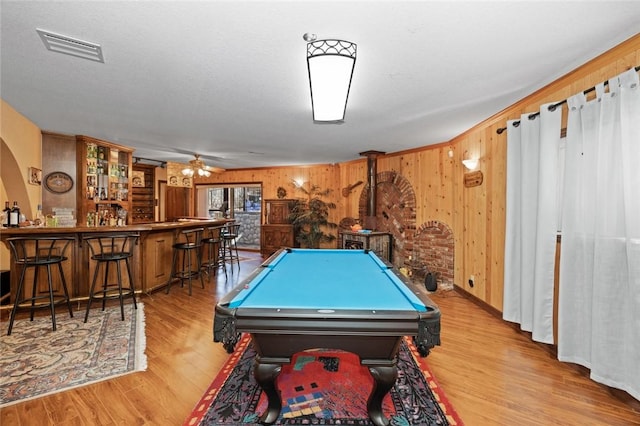 playroom with wooden walls, light hardwood / wood-style floors, billiards, and bar area