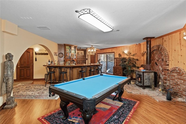 recreation room with bar area, light hardwood / wood-style flooring, a wood stove, and pool table