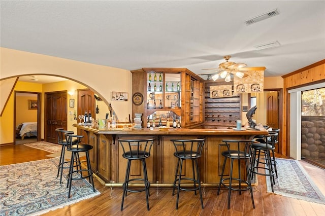 bar featuring hardwood / wood-style flooring, ceiling fan, and ornamental molding