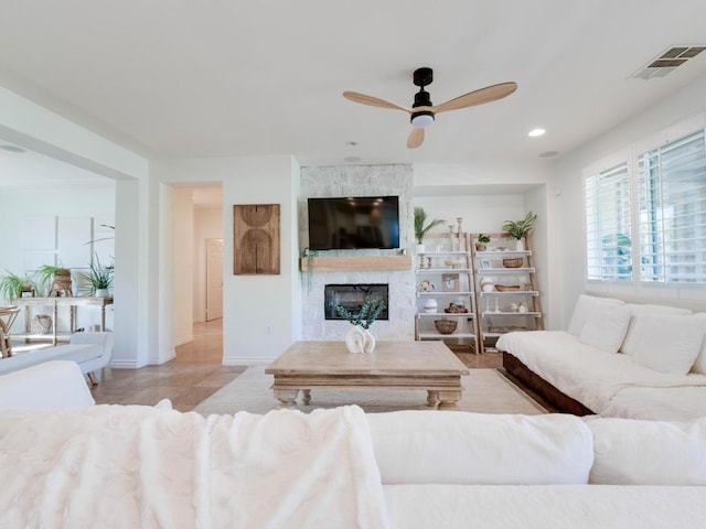 tiled living room featuring ceiling fan and a large fireplace