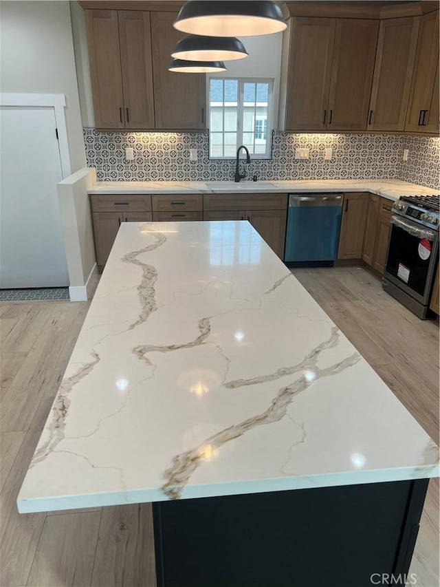 kitchen featuring tasteful backsplash, sink, stainless steel appliances, and light hardwood / wood-style floors