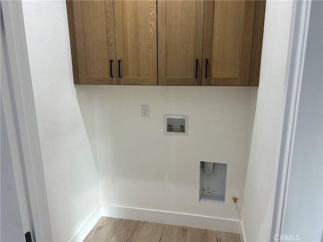 washroom featuring washer hookup, light hardwood / wood-style floors, and cabinets