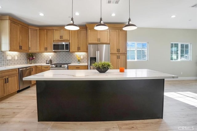 kitchen featuring pendant lighting, stainless steel appliances, a kitchen island, and light hardwood / wood-style flooring