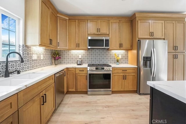 kitchen with decorative backsplash, light stone countertops, light wood-type flooring, stainless steel appliances, and sink