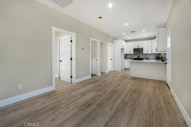 kitchen featuring kitchen peninsula, light hardwood / wood-style flooring, white cabinets, and appliances with stainless steel finishes