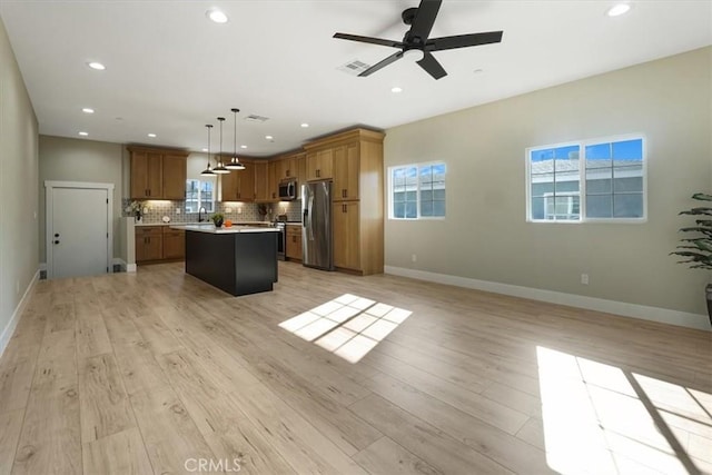 kitchen featuring stainless steel appliances, tasteful backsplash, light hardwood / wood-style floors, decorative light fixtures, and a kitchen island