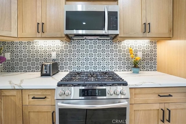 kitchen featuring light stone counters, light brown cabinetry, and appliances with stainless steel finishes