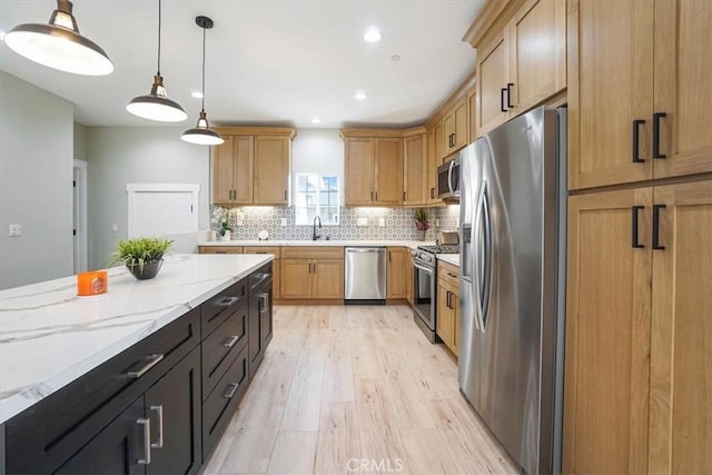 kitchen with hanging light fixtures, stainless steel appliances, light stone counters, light hardwood / wood-style floors, and decorative backsplash