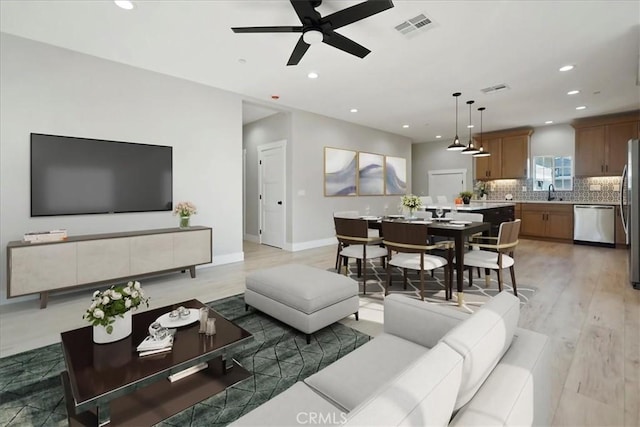 living room with hardwood / wood-style floors, ceiling fan, and sink