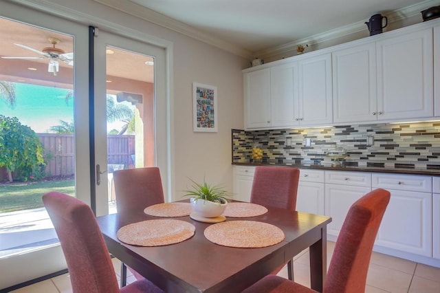 tiled dining space featuring crown molding and ceiling fan