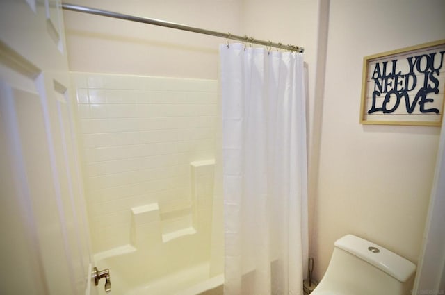 bathroom featuring shower / bath combination with curtain and toilet