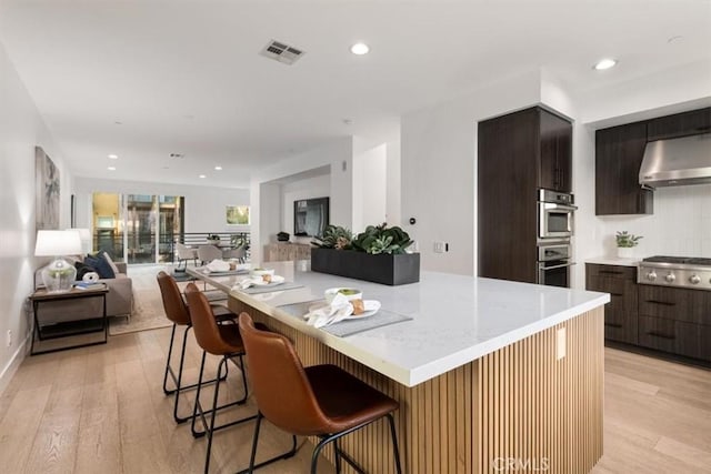 kitchen with open floor plan, light countertops, a center island, modern cabinets, and a kitchen bar