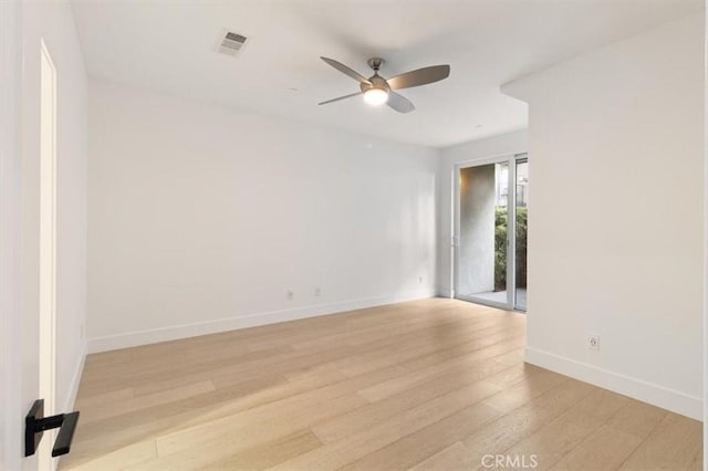 empty room with light wood-style floors, visible vents, baseboards, and a ceiling fan