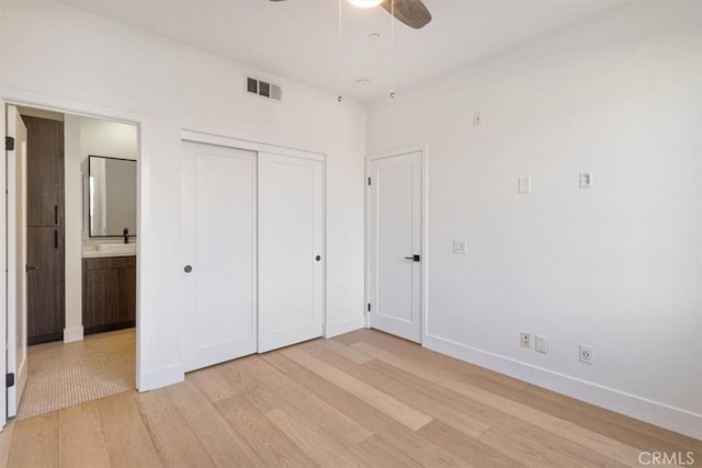 unfurnished bedroom with a closet, visible vents, light wood-style flooring, connected bathroom, and baseboards