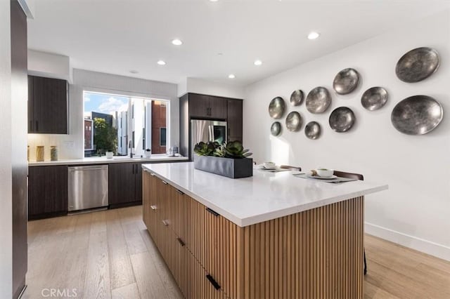 kitchen with modern cabinets, stainless steel appliances, light countertops, and a center island