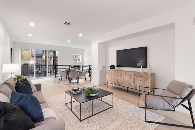 living area with light wood-style flooring, visible vents, baseboards, and recessed lighting