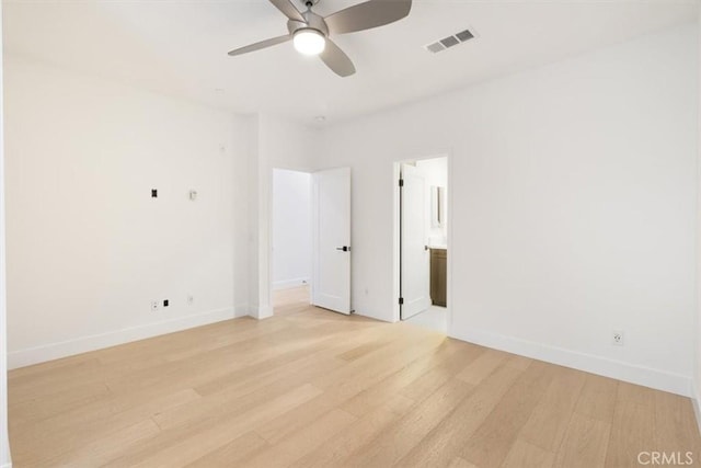 unfurnished room with light wood finished floors, visible vents, and baseboards