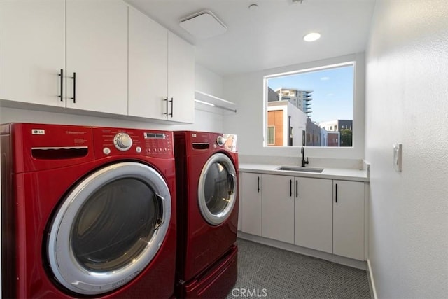 washroom with washing machine and dryer, a sink, cabinet space, and baseboards