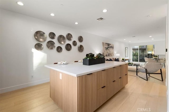 kitchen featuring a large island, light countertops, visible vents, open floor plan, and modern cabinets