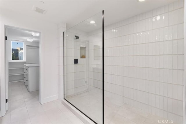 bathroom with a shower stall, a spacious closet, and tile patterned flooring