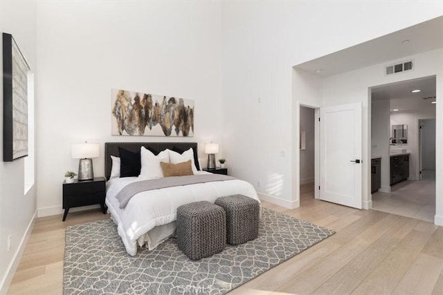 bedroom with a towering ceiling, light wood-style floors, and visible vents