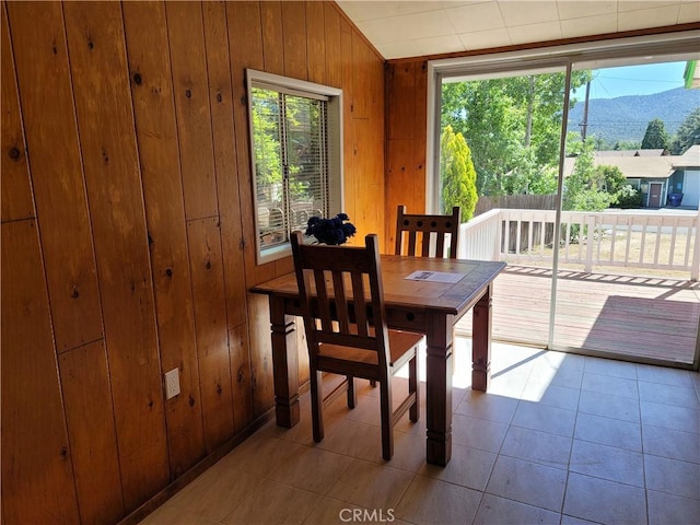 tiled dining area featuring a mountain view, a healthy amount of sunlight, lofted ceiling, and wood walls