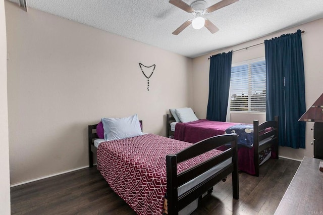 bedroom with ceiling fan, dark wood-type flooring, and a textured ceiling