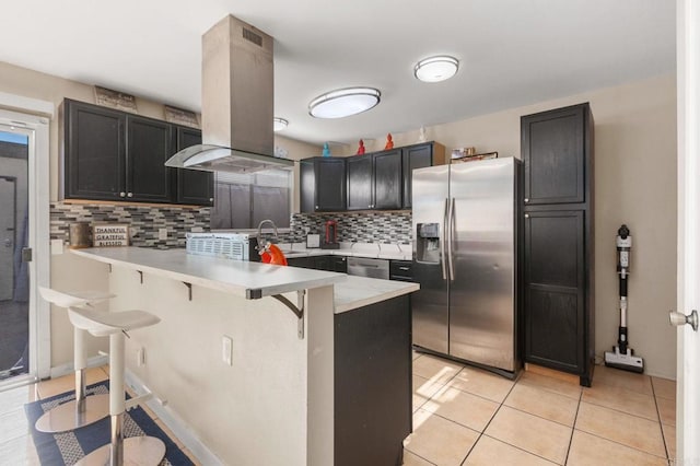 kitchen with a kitchen bar, stainless steel appliances, backsplash, kitchen peninsula, and island range hood