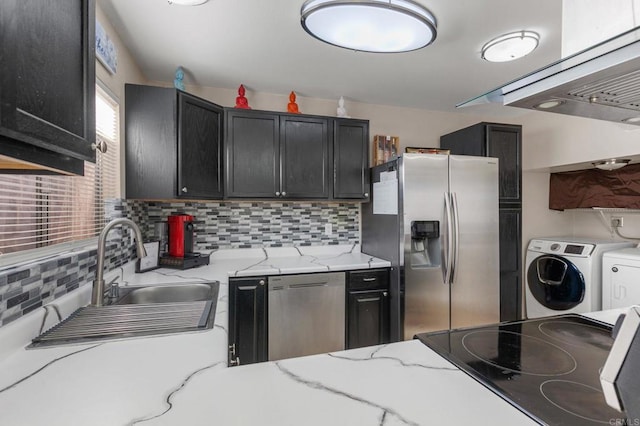 kitchen featuring sink, backsplash, light stone counters, washing machine and clothes dryer, and stainless steel appliances