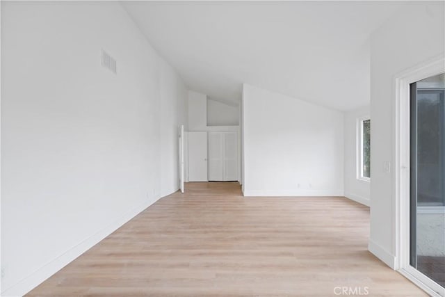 spare room featuring light wood-type flooring and vaulted ceiling