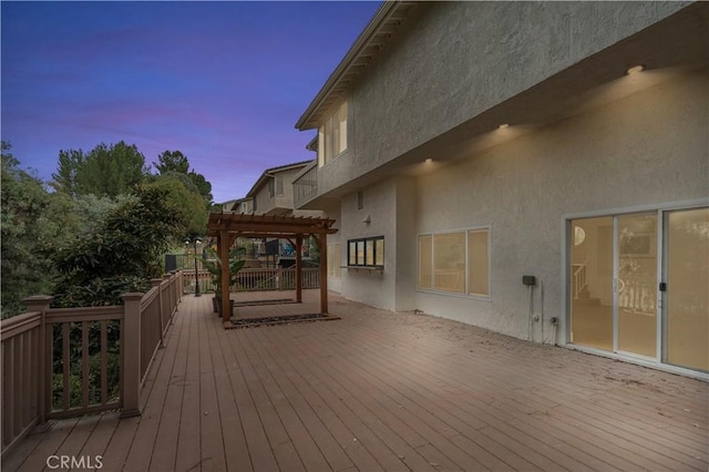 deck at dusk featuring a pergola