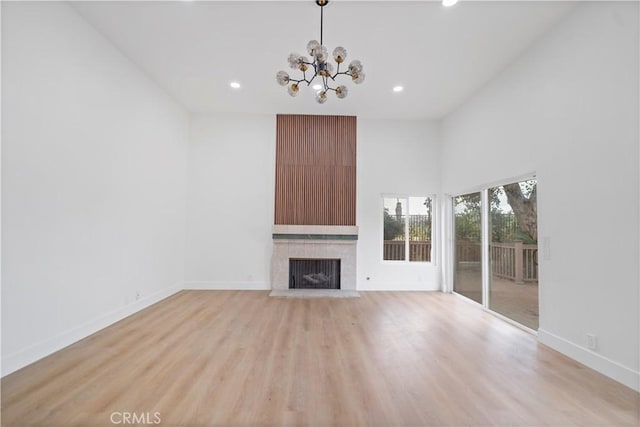 unfurnished living room with a chandelier, light hardwood / wood-style floors, and a fireplace