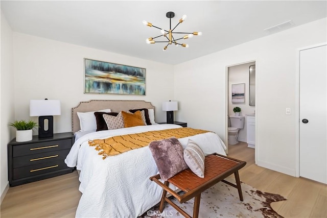 bedroom with ensuite bathroom, an inviting chandelier, and light hardwood / wood-style floors