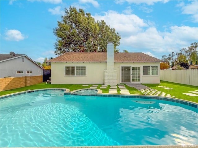 view of pool with a jacuzzi and a lawn