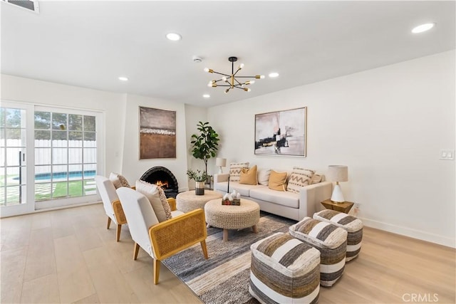 living room with light hardwood / wood-style floors, a fireplace, and an inviting chandelier