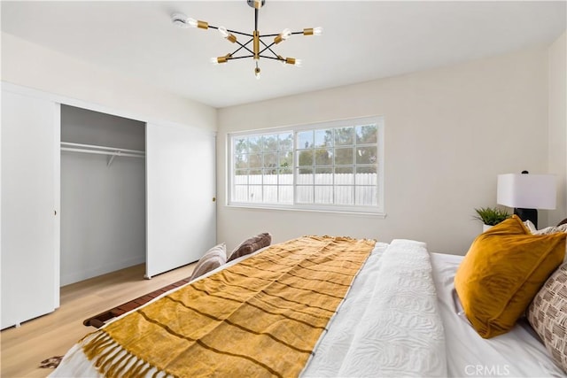 bedroom featuring a chandelier, light hardwood / wood-style floors, and a closet