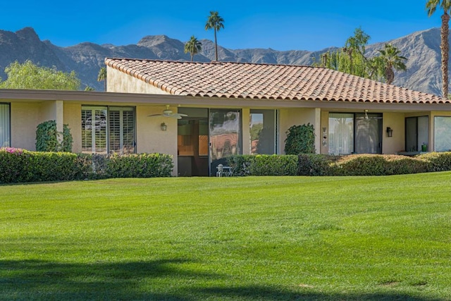 rear view of house featuring a lawn, a mountain view, and ceiling fan