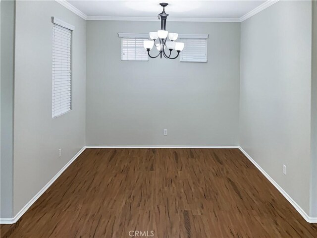 empty room featuring dark hardwood / wood-style flooring, crown molding, and a notable chandelier