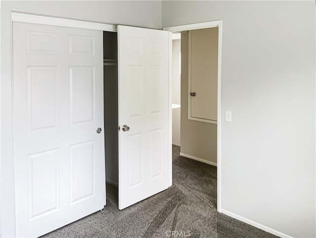 unfurnished bedroom featuring dark carpet and a closet