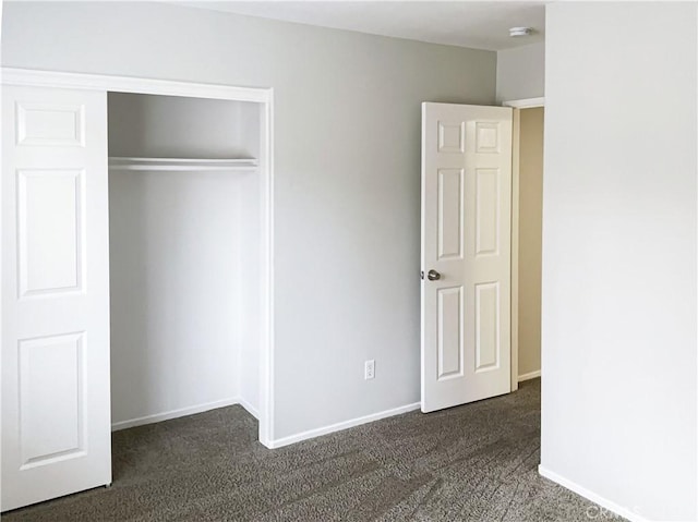 unfurnished bedroom with dark colored carpet and a closet