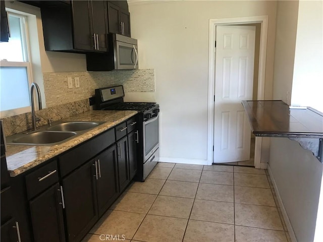 kitchen featuring backsplash, sink, appliances with stainless steel finishes, light tile patterned flooring, and light stone counters