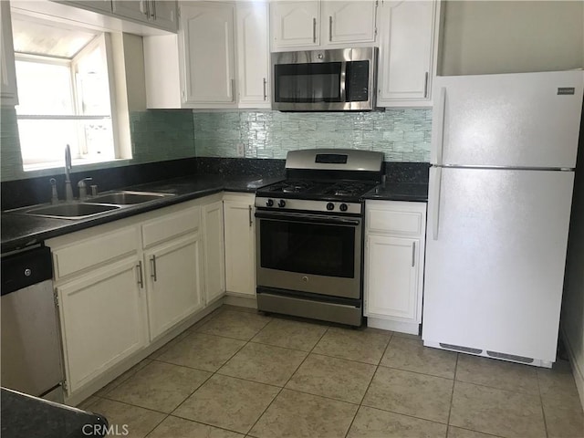 kitchen featuring appliances with stainless steel finishes, backsplash, sink, light tile patterned floors, and white cabinetry