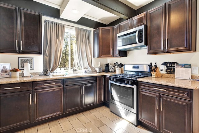 kitchen featuring dark brown cabinets, sink, light stone counters, and stainless steel appliances